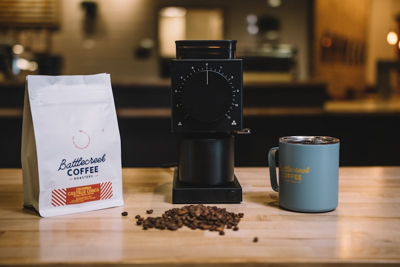 An airtight coffee storage canister on a counter with a scoop and whole beans beside it.